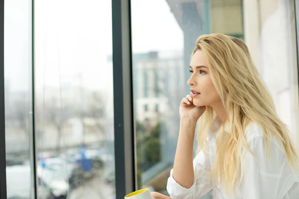 Beautiful blonde woman next to a window — Stock Photo, Image