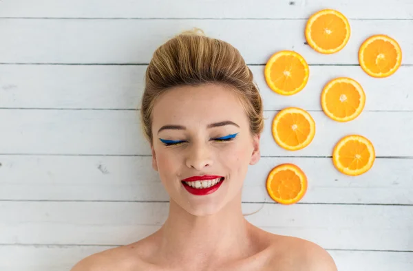 Blonde vrouw leggen naast segmenten van Oranje — Stockfoto