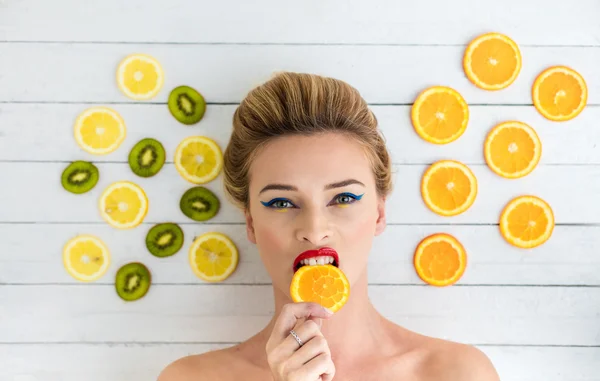 Sarışın kadın portakal, limon ve kivi dilimlerini yanındaki döşeme — Stok fotoğraf