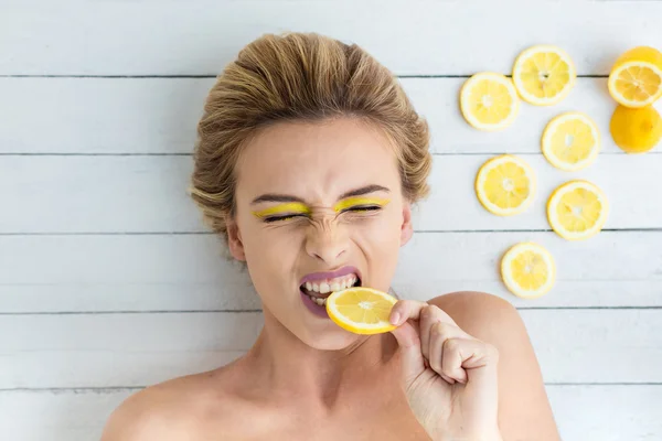 Donna bionda sdraiata accanto a fette di limone — Foto Stock