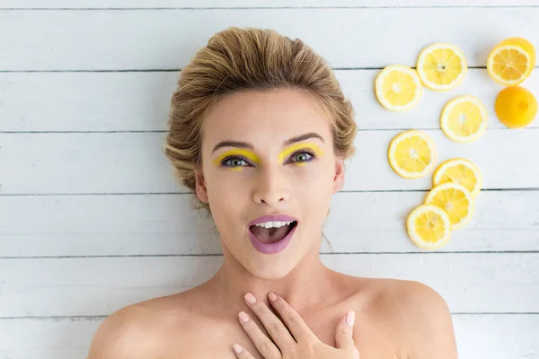 Blonde woman laying next to slices of lemon — Stock Photo, Image