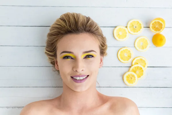 Blonde vrouw leggen naast de plakjes citroen — Stockfoto