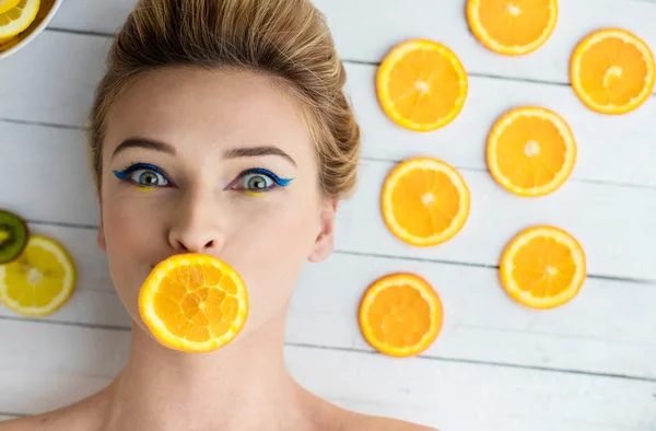 Blonde vrouw leggen naast segmenten van Oranje — Stockfoto