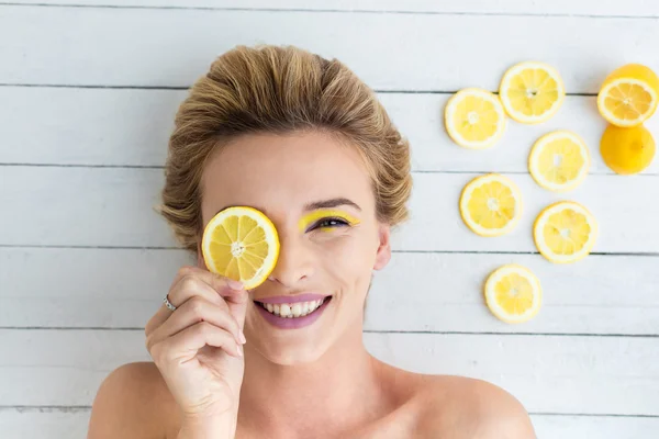 Blonde woman laying next to slices of lemon — Stock Photo, Image