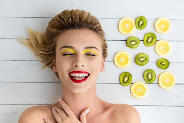 Blonde vrouw leggen naast de plakjes citroen en kiwi — Stockfoto
