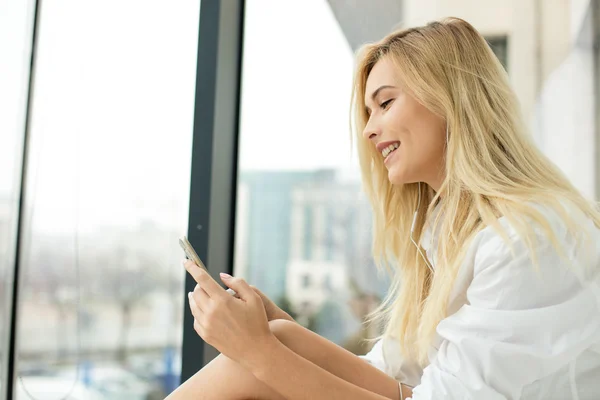 Hermosa mujer rubia al lado de una ventana — Foto de Stock