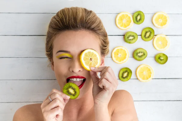 Blondine liegt neben Zitronen- und Kiwi-Scheiben — Stockfoto