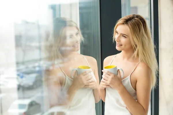 Mooie blonde vrouw naast een venster — Stockfoto