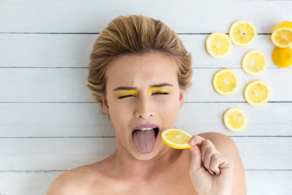 Blonde woman laying next to slices of lemon — Stock Photo, Image