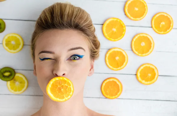 Mulher loira que coloca ao lado de fatias de laranja — Fotografia de Stock