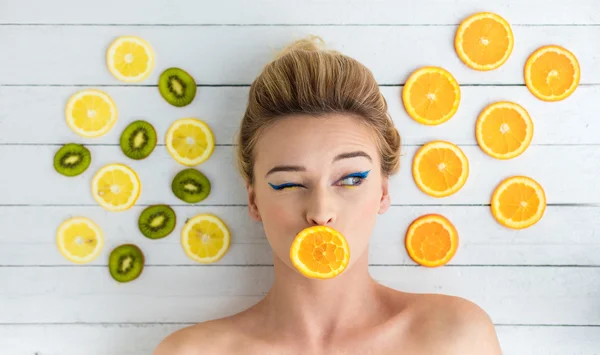 Sarışın kadın portakal, limon ve kivi dilimlerini yanındaki döşeme — Stok fotoğraf