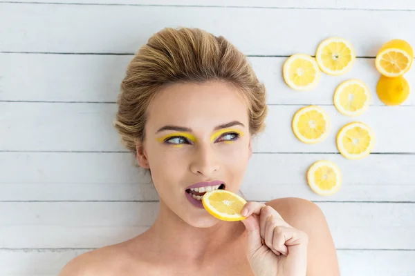 Mulher loira que coloca ao lado de fatias de limão — Fotografia de Stock