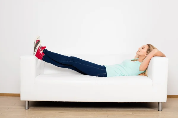 Mujeres rubias sentadas en el sofá con una almohada —  Fotos de Stock