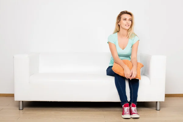 Blonde vrouwen zittend op de Bank met een kussen — Stockfoto