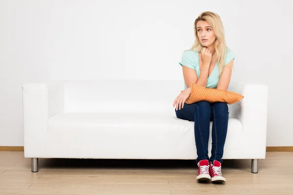 Blonde vrouwen zittend op de Bank met een kussen — Stockfoto