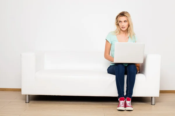 Blonde women sitting on couch with a pillow — Fotografie, imagine de stoc