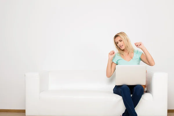 Blond ženy sedí na gauči s polštářem — Stock fotografie