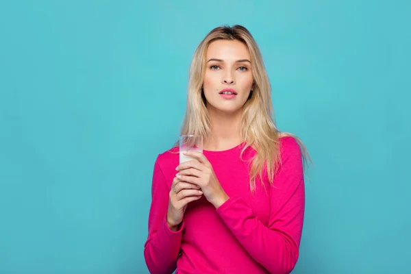 Blonde junge Frau ein Glas Milch auf blau — Stockfoto