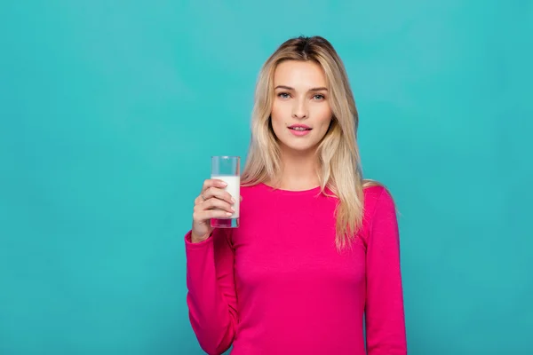 Blonde jonge vrouw een glas melk op blauw — Stockfoto