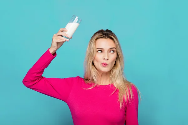 Blonde junge Frau ein Glas Milch auf blau — Stockfoto