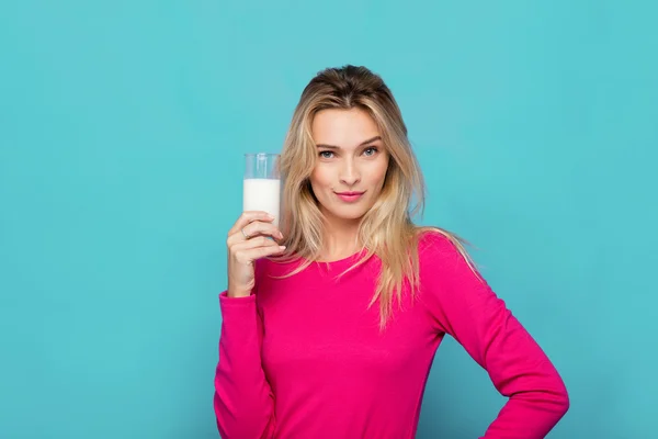 Blonde jonge vrouw een glas melk op blauw — Stockfoto