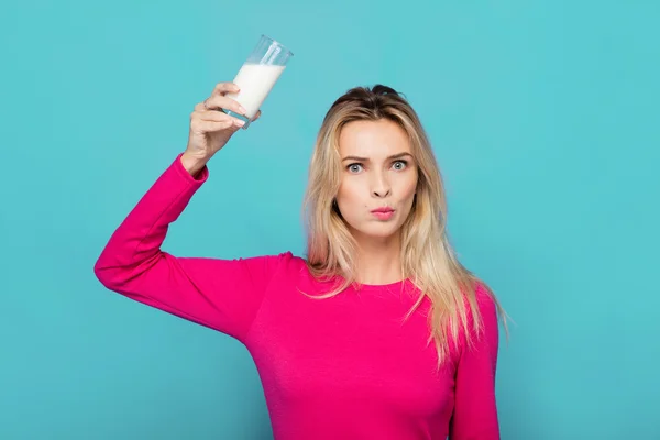 Blondýnka mladá žena sklenici mléka na modré — Stock fotografie