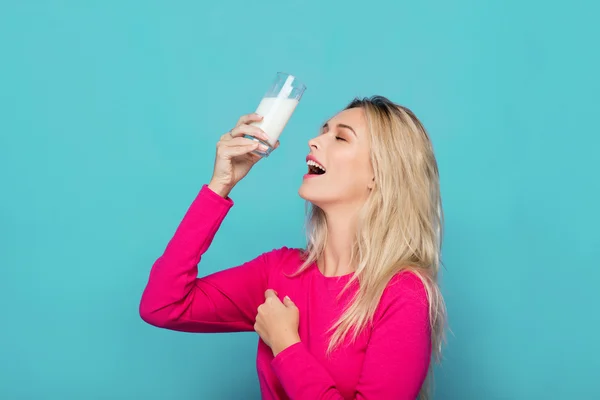 Blond ung kvinna ett glas mjölk på blå — Stockfoto