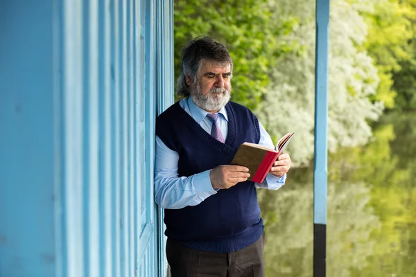 Velho com um livro em um alpendre — Fotografia de Stock