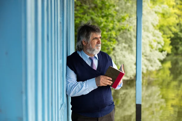 Anciano con un libro en un porche — Foto de Stock