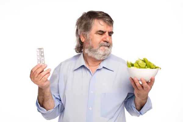 Старик с таблетками и салатом — стоковое фото
