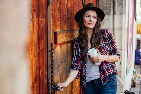 Mujer joven con un sombrero al lado de una vieja puerta de madera — Foto de Stock