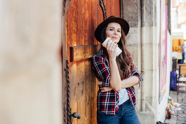 Молодая женщина в шляпе рядом со старой деревянной дверью — стоковое фото