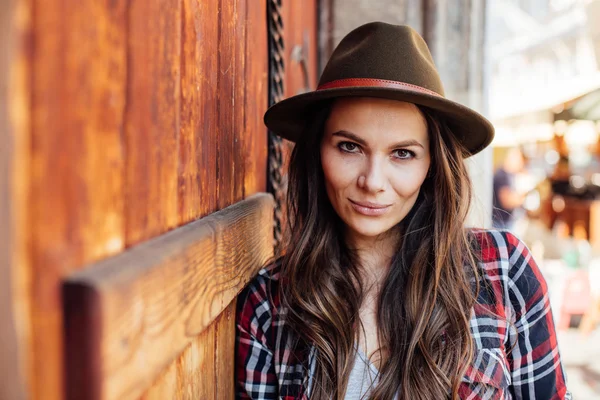 Mujer joven con un sombrero al lado de una vieja puerta de madera — Foto de Stock