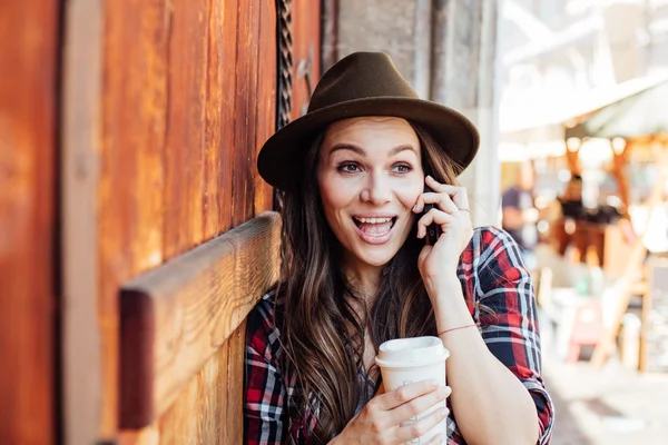 Молодая женщина в шляпе рядом со старой деревянной дверью разговаривает в чел — стоковое фото