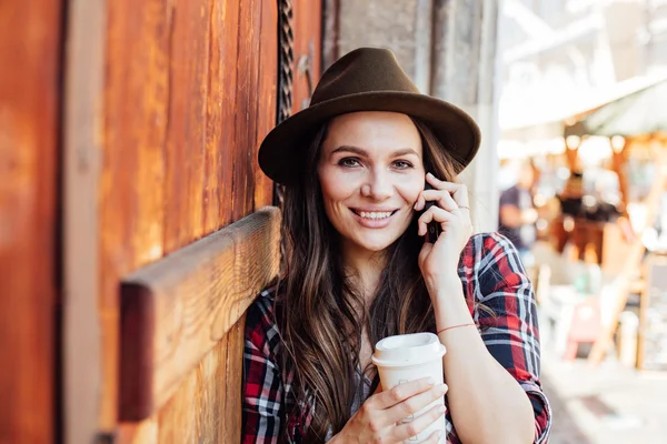 Junge Frau mit Hut neben einer alten Holztür im Gespräch bei cel — Stockfoto