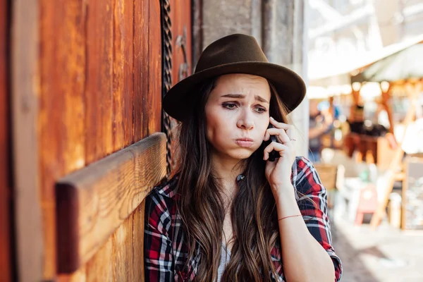 Jonge vrouw met een hoed naast een oude houten deur praten op cel — Stockfoto