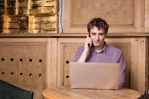 Jonge man aan het werk bij computer in een pub — Stockfoto