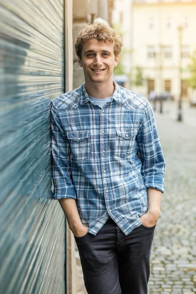 Молодой человек в клетчатой рубашке стоит снаружи — стоковое фото