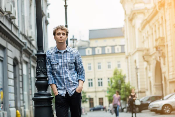 Молодой человек в клетчатой рубашке стоит снаружи — стоковое фото