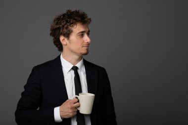 gri arka plan üzerine bir fincan ile takım elbiseli şık adam