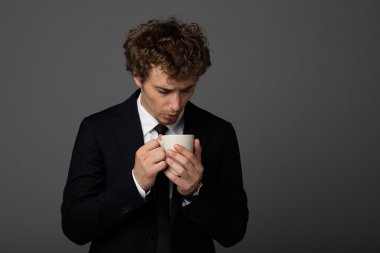gri arka plan üzerine bir fincan ile takım elbiseli şık adam