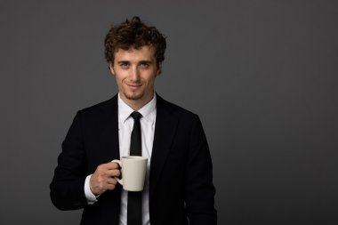 gri arka plan üzerine bir fincan ile takım elbiseli şık adam