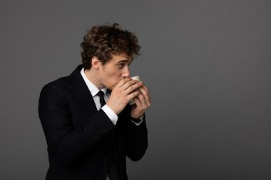 gri arka plan üzerine bir fincan ile takım elbiseli şık adam