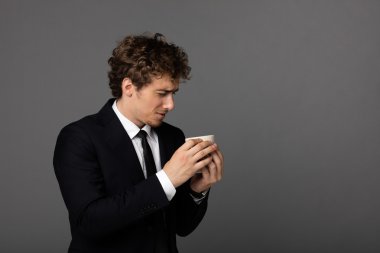 gri arka plan üzerine bir fincan ile takım elbiseli şık adam