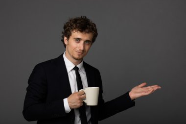 gri arka plan üzerine bir fincan ile takım elbiseli şık adam