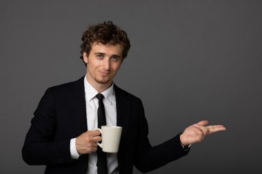gri arka plan üzerine bir fincan ile takım elbiseli şık adam