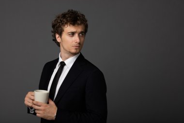 gri arka plan üzerine bir fincan ile takım elbiseli şık adam
