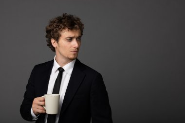 gri arka plan üzerine bir fincan ile takım elbiseli şık adam
