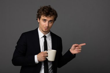 gri arka plan üzerine bir fincan ile takım elbiseli şık adam