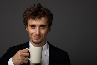 gri arka plan üzerine bir fincan ile takım elbiseli şık adam